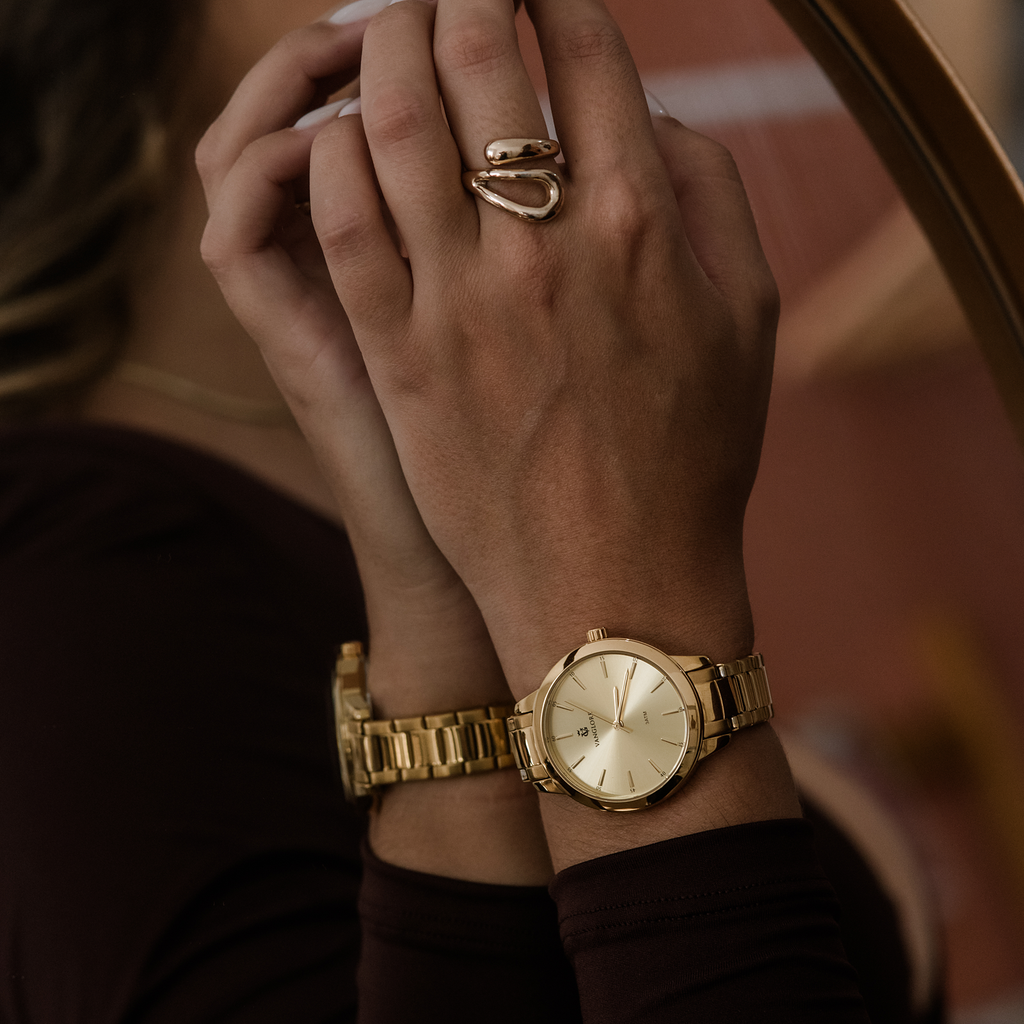 Relógio feminino Vanglore Essence dourado 36mm, no pulso, em frente ao espelho