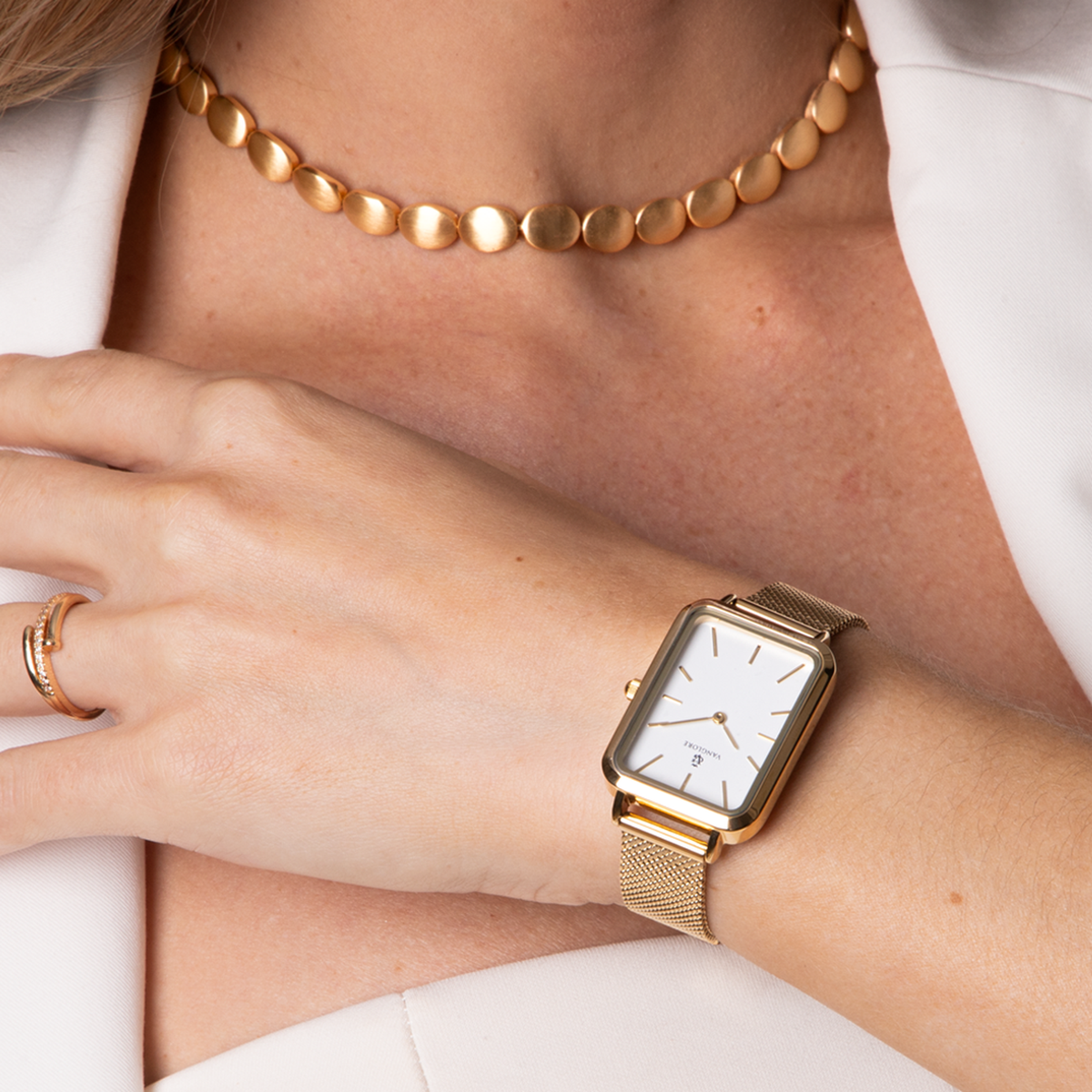 Relógio feminino Vanglore Lunna dourado com fundo branco, caixa retangular e pulseira mesh, no pulso